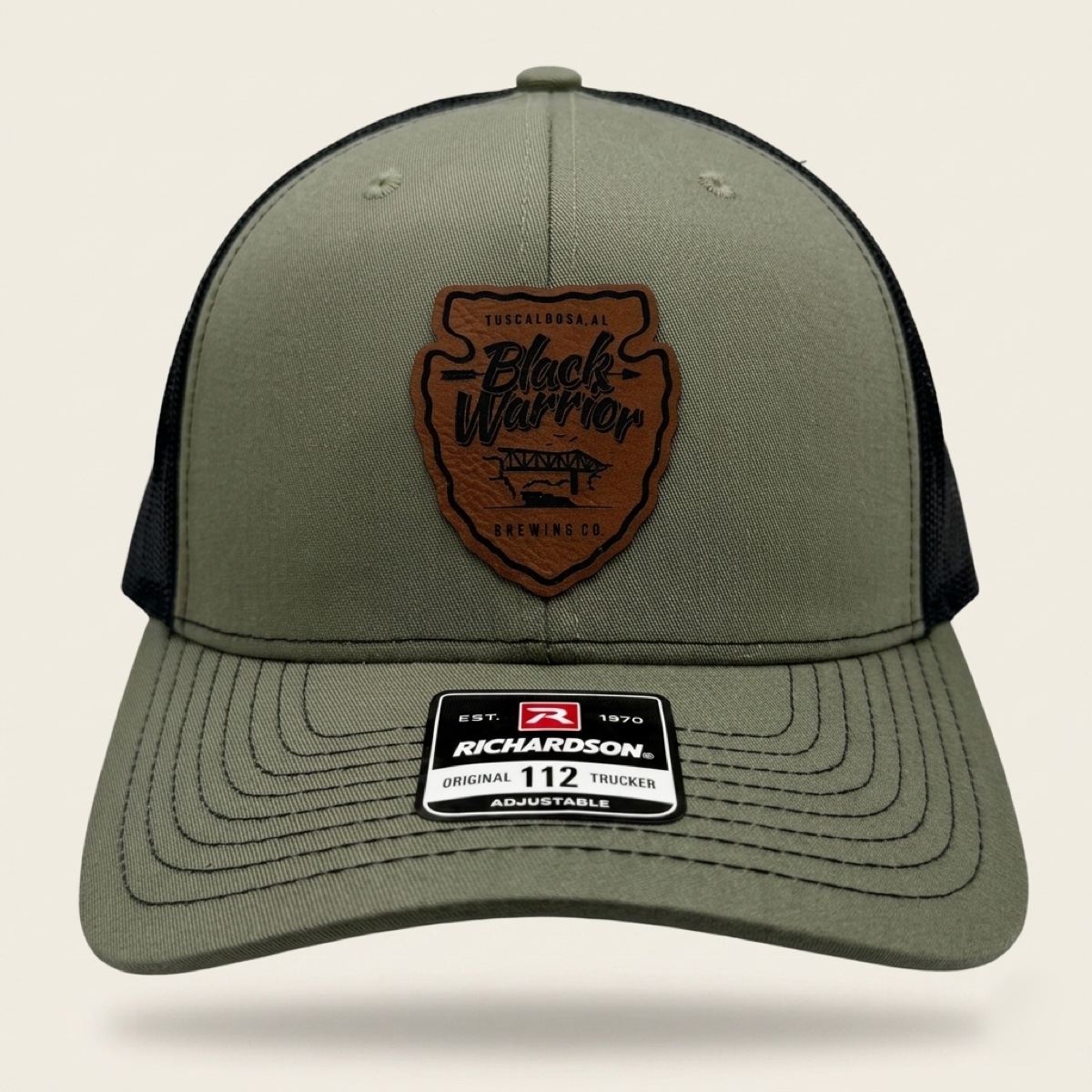Loden green and black Richardson trucker cap with engraved Black Warrior Brewing Co. arrowhead logo patch