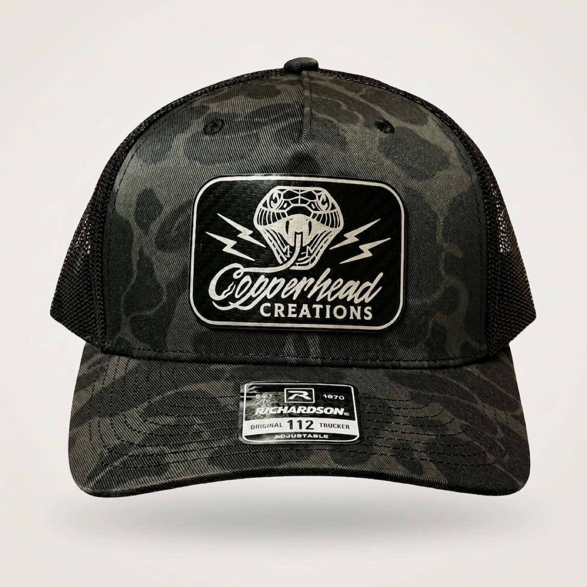 Copperhead Creations black camo Richardson trucker cap with engraved carbon fiber snake logo patch