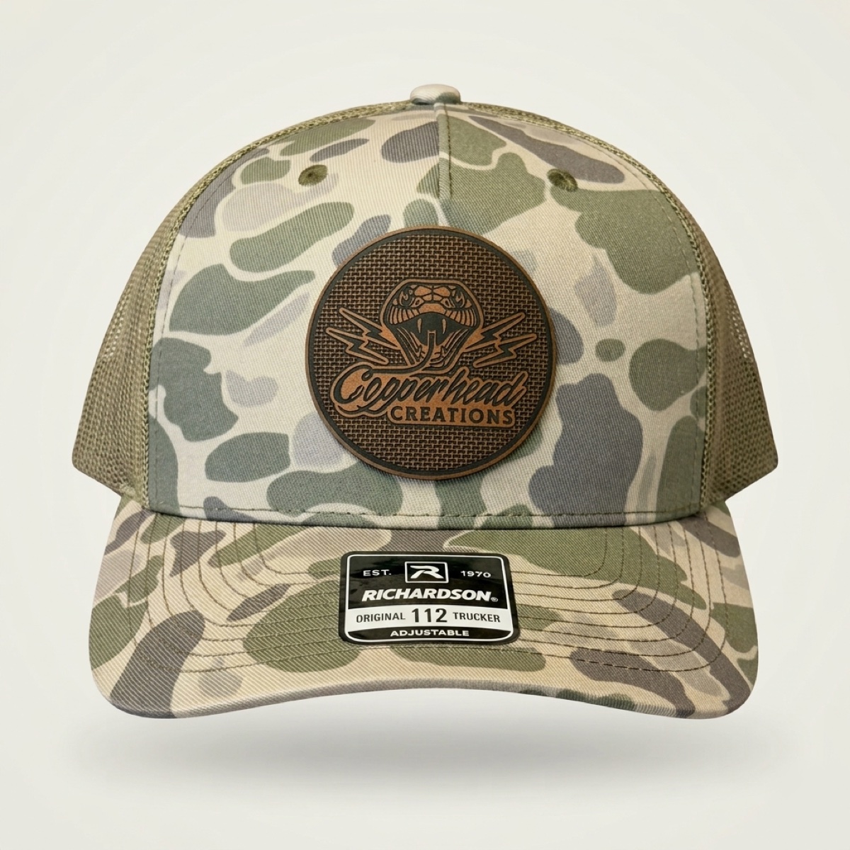Copperhead Creations light duck camo trucker cap with engraved leatherette snake logo patch