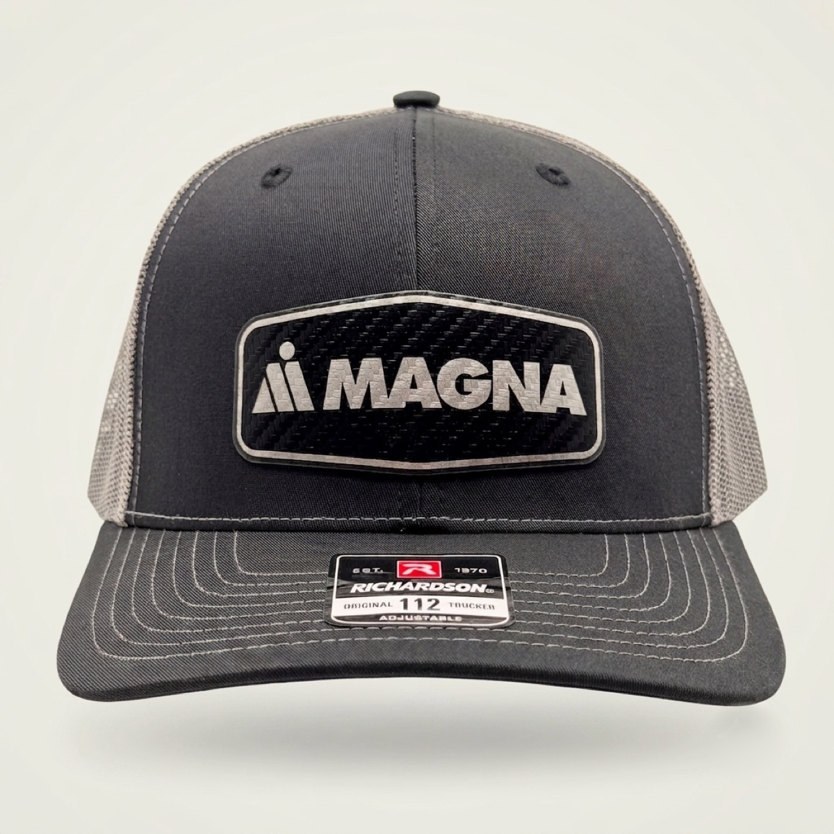 Charcoal and gray Richardson trucker cap with engraved Magna carbon fiber logo patch